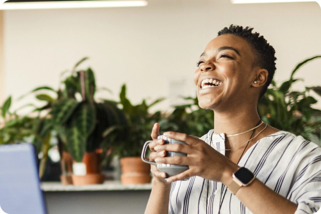 woman laughing wit holding coffee mug