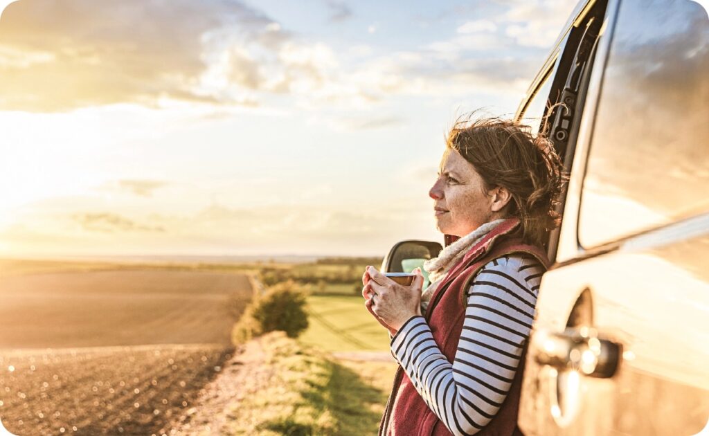 woman holding a coffee cup and watching towards field